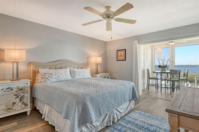 bedroom with a water view, ceiling fan, and hardwood / wood-style flooring