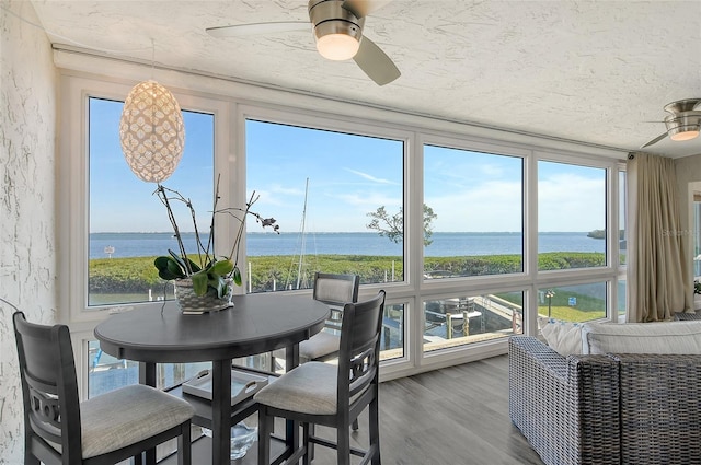 sunroom / solarium featuring a water view, a wealth of natural light, and ceiling fan