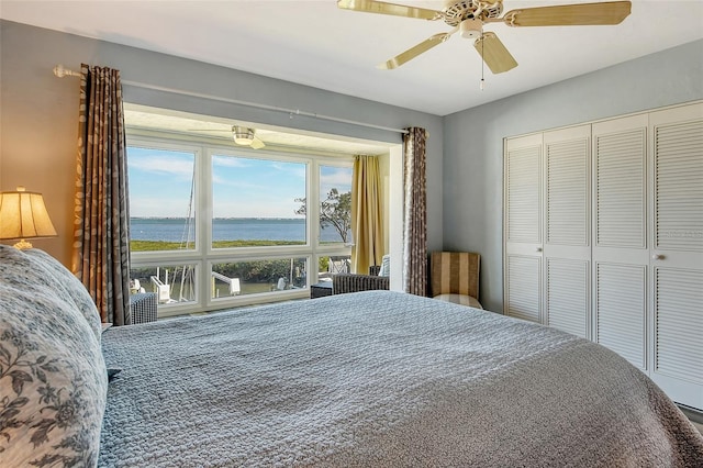 bedroom with ceiling fan, a closet, and a water view