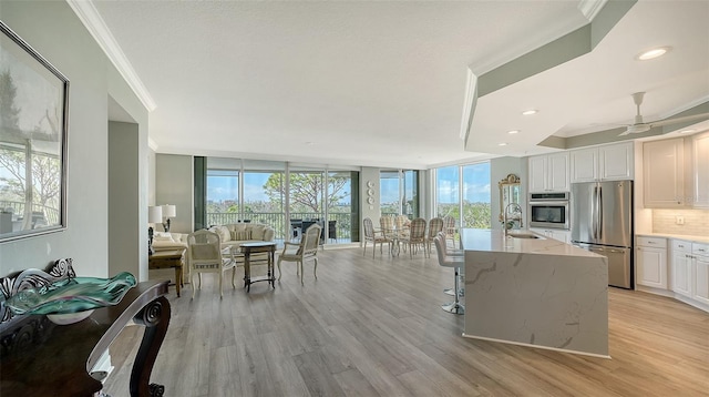 kitchen with white cabinets, a center island with sink, light stone countertops, and stainless steel appliances