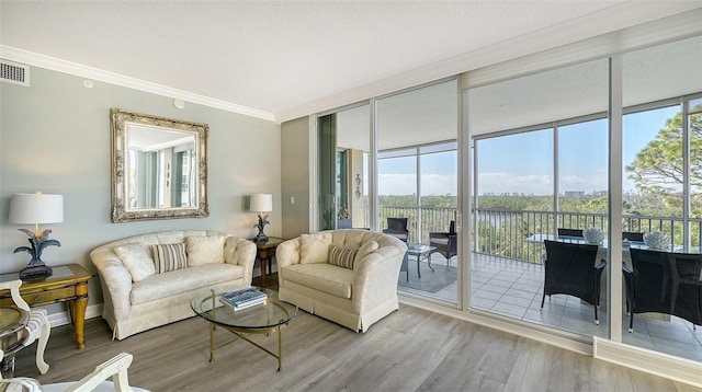 living room with hardwood / wood-style flooring, plenty of natural light, expansive windows, and ornamental molding