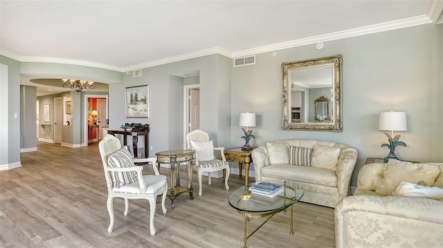 living room featuring light wood-type flooring, ornamental molding, and a chandelier