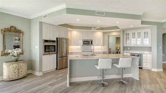 kitchen with white cabinets, sink, wine cooler, light stone countertops, and appliances with stainless steel finishes