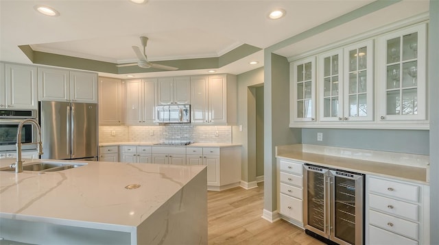 kitchen with ceiling fan, beverage cooler, light stone counters, white cabinets, and appliances with stainless steel finishes