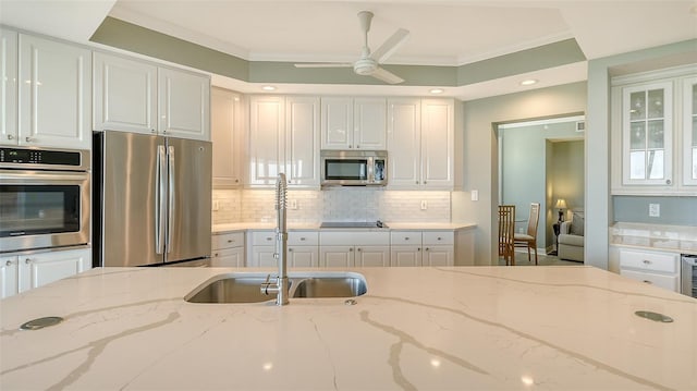 kitchen featuring white cabinets, crown molding, light stone countertops, and stainless steel appliances