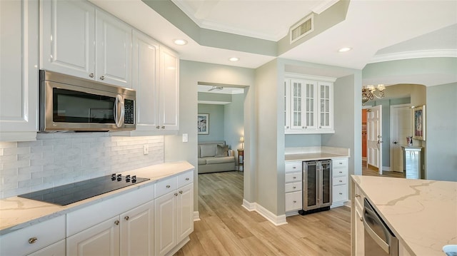 kitchen with stainless steel appliances, white cabinetry, beverage cooler, and crown molding