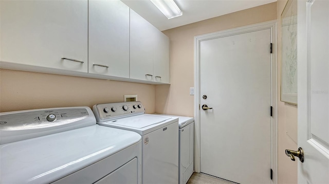 clothes washing area featuring cabinets and washing machine and clothes dryer