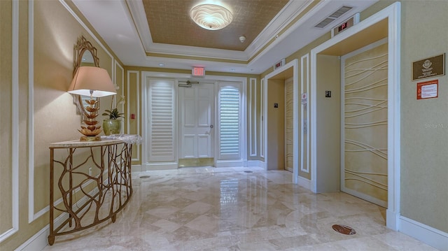 hall with a tray ceiling, elevator, and ornamental molding