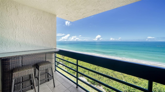 balcony featuring a beach view and a water view