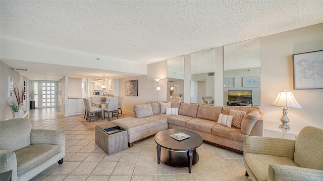 living room featuring a textured ceiling, a notable chandelier, and light tile patterned flooring