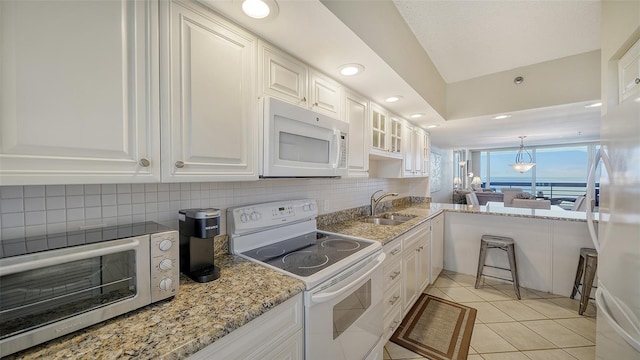 kitchen with light tile patterned floors, white cabinets, white appliances, and sink