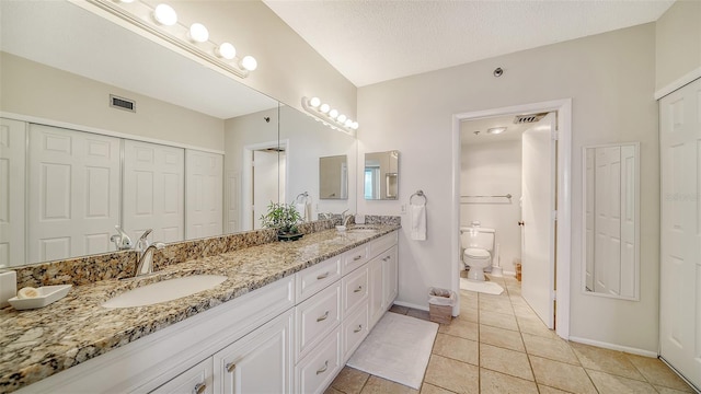 bathroom with tile patterned flooring, vanity, a textured ceiling, and toilet