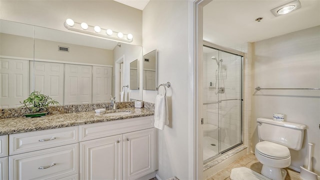 bathroom featuring tile patterned flooring, toilet, vanity, and walk in shower