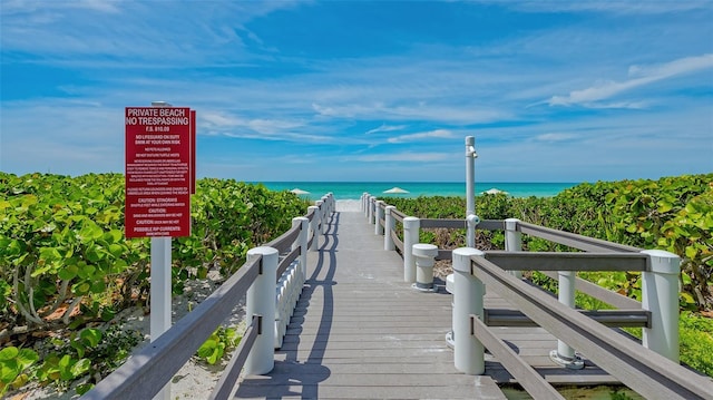 view of property's community featuring a water view and a beach view