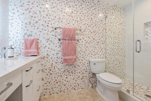 bathroom with tile patterned floors, a shower with shower door, toilet, and vanity