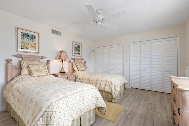 bedroom featuring light wood-type flooring, multiple closets, and ceiling fan