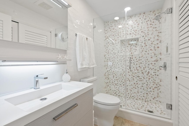 bathroom with tile walls, vanity, a shower with door, and toilet