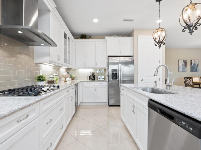 kitchen featuring a sink, white cabinetry, appliances with stainless steel finishes, wall chimney exhaust hood, and glass insert cabinets