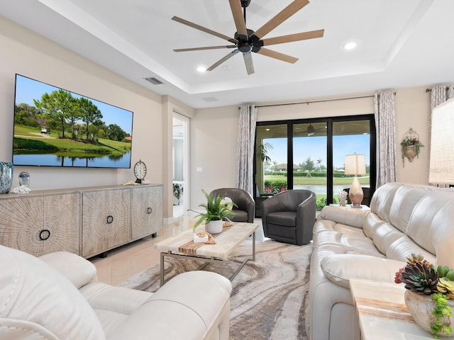 living room with a water view, a tray ceiling, and recessed lighting