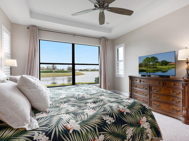 bedroom with a ceiling fan, a raised ceiling, carpet flooring, and baseboards