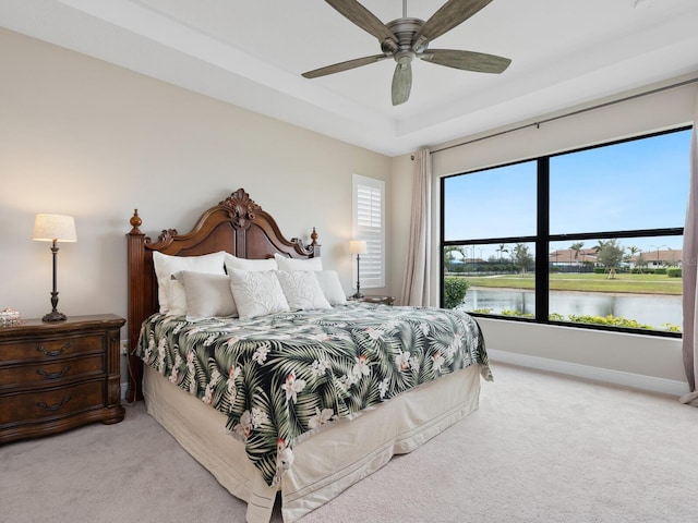 bedroom with a water view, ceiling fan, baseboards, and light colored carpet