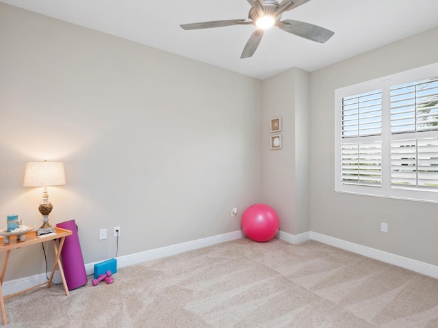 exercise area with light carpet, ceiling fan, and baseboards