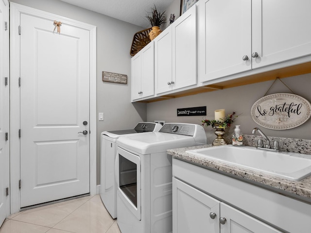 laundry room featuring light tile patterned floors, cabinet space, a sink, a textured ceiling, and independent washer and dryer