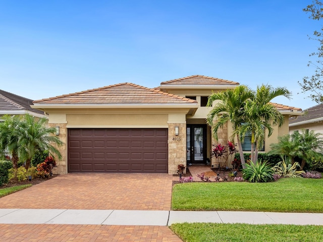 prairie-style house with decorative driveway, an attached garage, a tile roof, and stucco siding