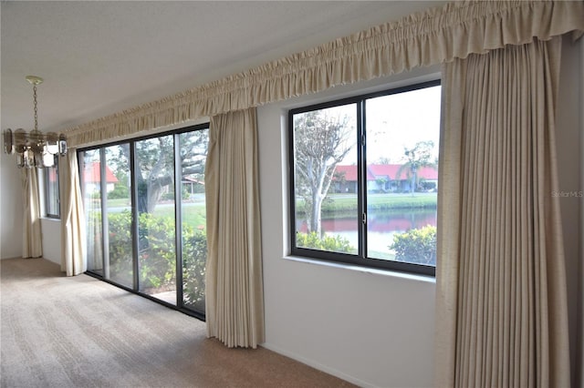 unfurnished room featuring plenty of natural light, carpet, and a notable chandelier