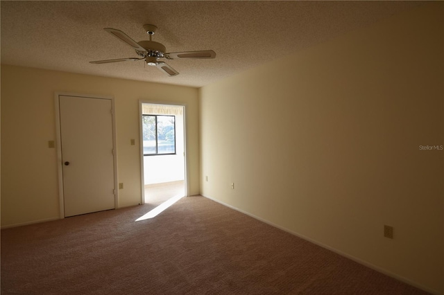 carpeted spare room featuring ceiling fan and a textured ceiling