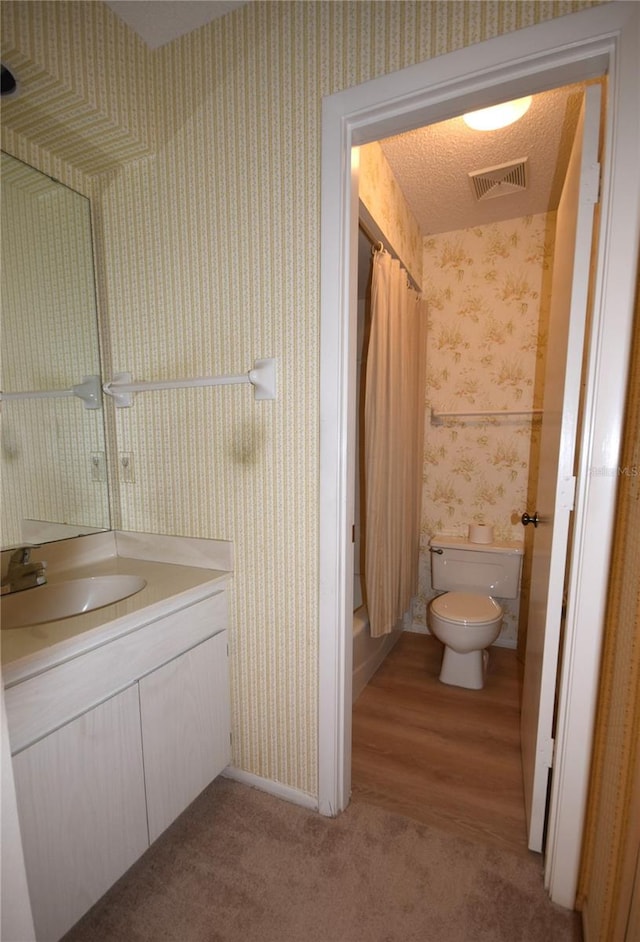 bathroom featuring hardwood / wood-style floors, vanity, a textured ceiling, and toilet