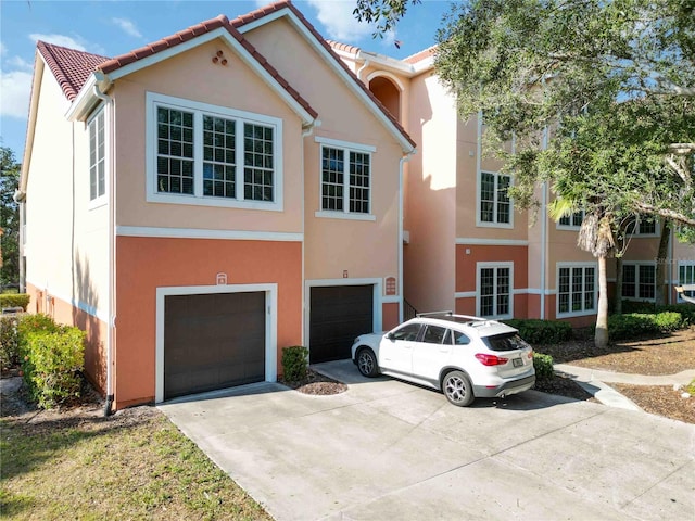 view of front of property featuring driveway, an attached garage, a tile roof, and stucco siding