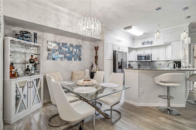 dining area with light wood-style floors and crown molding