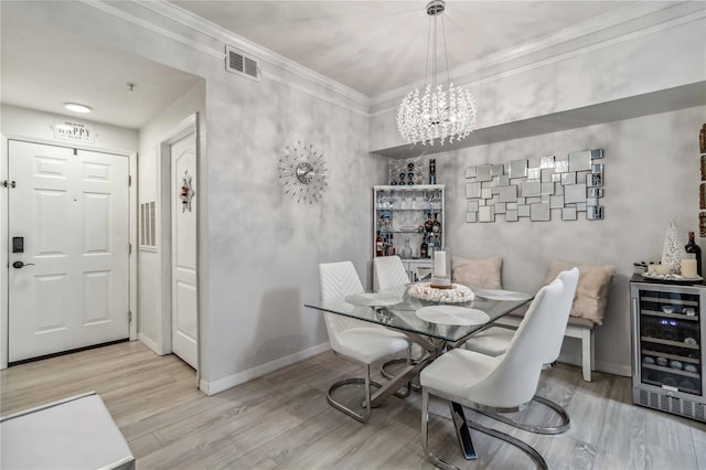 dining space with beverage cooler, baseboards, light wood-style flooring, crown molding, and a notable chandelier