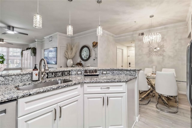 kitchen featuring ornamental molding, white cabinets, a sink, and hanging light fixtures