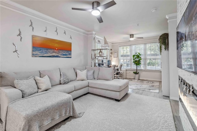 living area featuring a ceiling fan, crown molding, baseboards, and wood finished floors