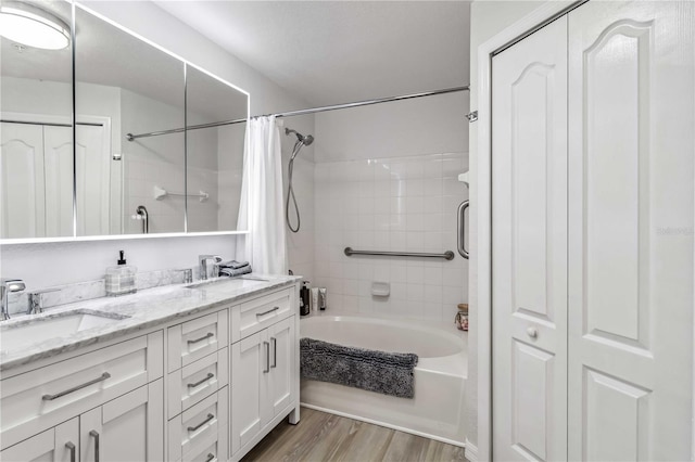 bathroom featuring a closet, shower / bath combo, a sink, and wood finished floors