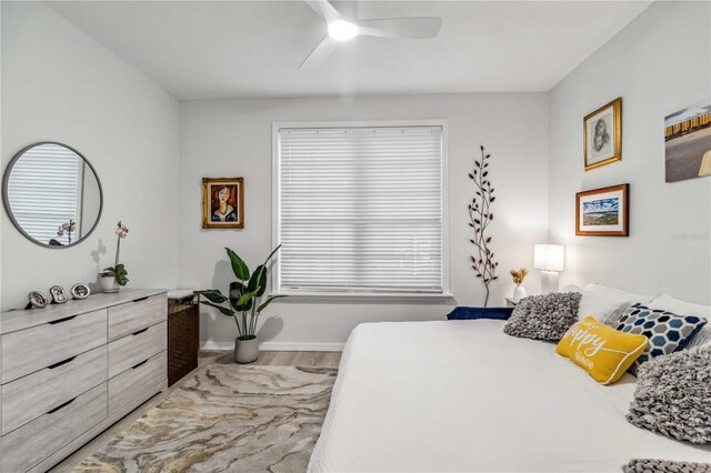 bedroom with ceiling fan, wood finished floors, and baseboards