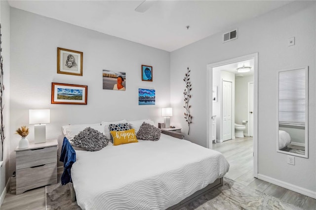 bedroom with ensuite bath, light wood-style flooring, visible vents, and baseboards