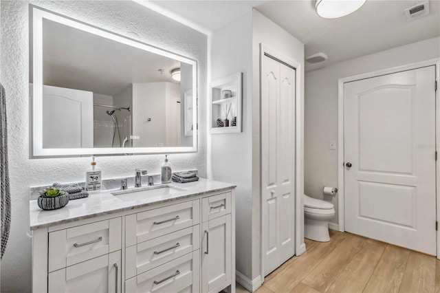 bathroom featuring a closet, walk in shower, vanity, and wood finished floors