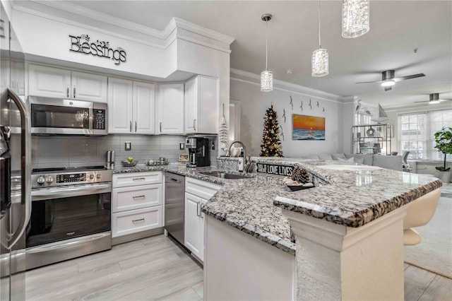 4106 Central Sarasota Pkwy Unit 1013, Sarasota, FL 34238 - kitchen with appliances with stainless steel finishes, a peninsula, ornamental molding, white cabinetry, and backsplash
