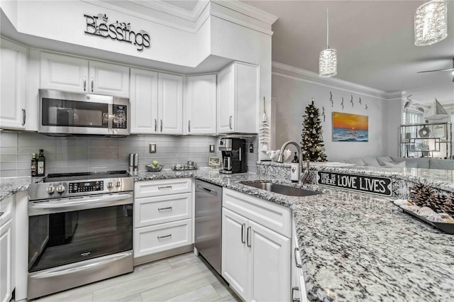 kitchen with stainless steel appliances, white cabinets, a sink, and crown molding