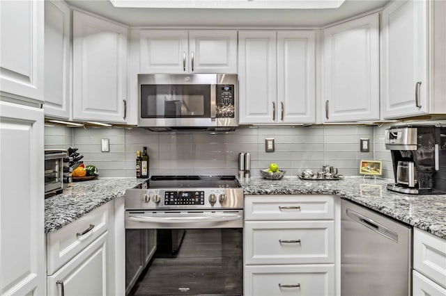 kitchen featuring stainless steel appliances, white cabinets, light stone counters, and tasteful backsplash