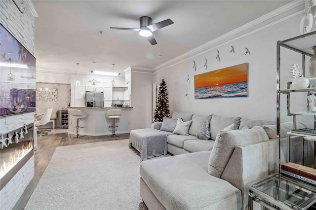 living room featuring ornamental molding, light wood-style floors, and ceiling fan