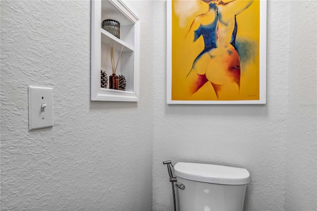 bathroom featuring toilet and a textured wall