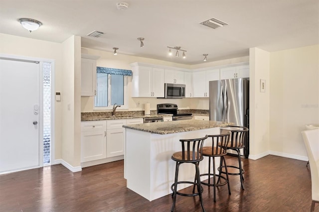 kitchen featuring dark wood-type flooring, a center island, white cabinets, and stainless steel appliances