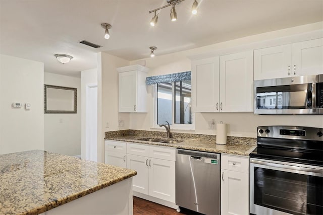 kitchen with sink, dark wood-type flooring, stainless steel appliances, light stone counters, and white cabinets