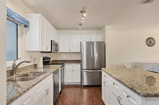 kitchen with appliances with stainless steel finishes, light stone counters, dark wood-type flooring, sink, and white cabinets