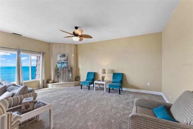 carpeted living room with ceiling fan and a water view