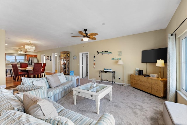 carpeted living room with ceiling fan with notable chandelier